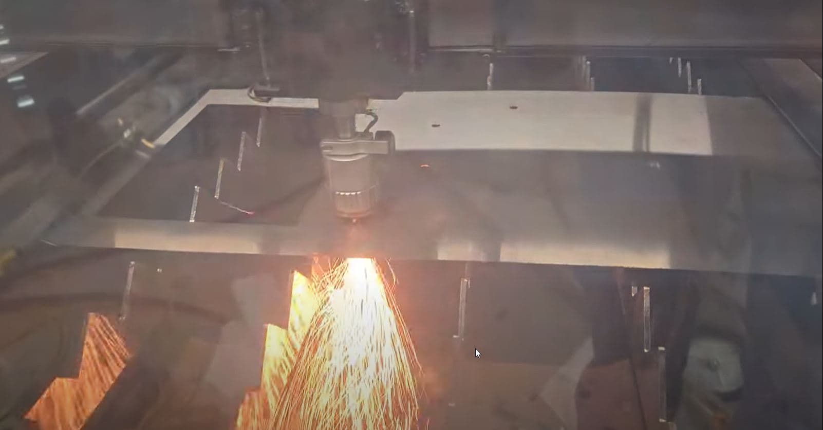 Laser table cutting a metal plate with sparks in the CNC Powder shop